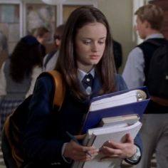 a young woman holding a binder in her hand and looking down at the folder she is holding