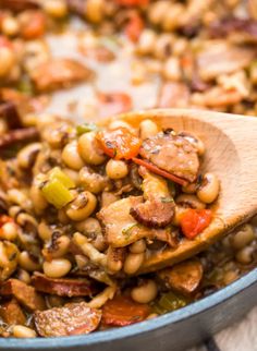 a wooden spoon filled with beans and sausage