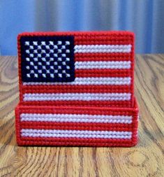 a red, white and blue knitted american flag pin cushion sitting on a wooden table