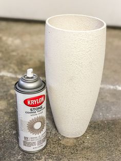 a white vase sitting next to a can of spray paint on top of a cement floor