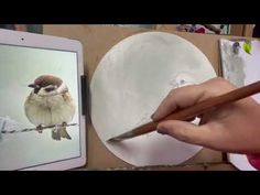 a person holding a pencil in front of an ipad with a bird on it