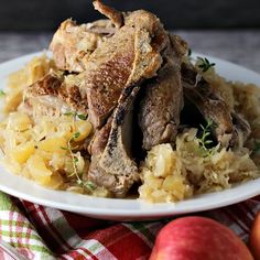 a white plate topped with meat and rice next to apples