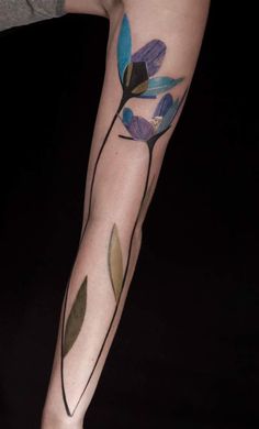 a woman's arm with tattoos on it and flowers painted on the side of her arm