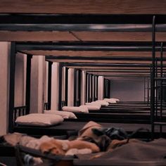 there are many bunk beds in this room with blankets on the floor and one bed is empty