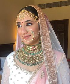 a woman in a bridal outfit with jewelry on her head and nose ring, smiling at the camera