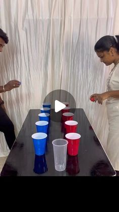 two people standing at a table with cups on it