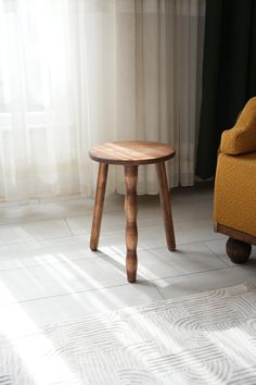 a small wooden table sitting on top of a white floor next to a yellow chair