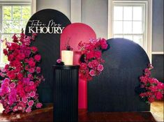 pink flowers are on display in front of a black sculpture with the words khoury