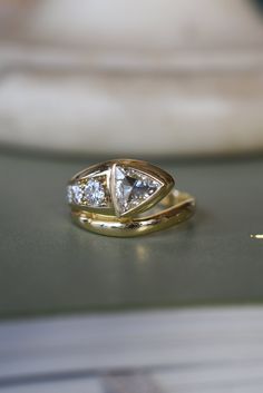 two gold rings with diamonds on top of a table in front of a white vase