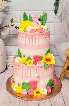 a three tiered cake decorated with flowers and fruit is on a wooden stand in front of a white tile wall