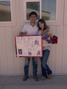 a man and woman standing next to each other holding a sign