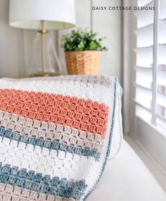 a crocheted blanket sitting on top of a white couch next to a lamp