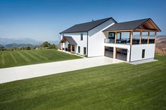 an aerial view of a modern home in the country side with grass and mountains in the background