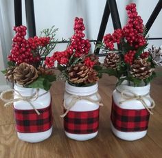 three mason jars decorated with pine cones and red berries