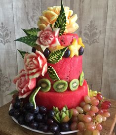 a watermelon and kiwi fruit cake with grapes, grapefruits, and flowers