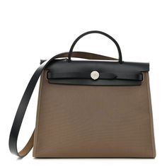 This is an authentic HERMES Vache Hunter Toile Herbag Zip 31 PM in Etoupe and Ebene.This stylish shoulder bag is crafted of sturdy taupe canvas and features a black leather top crest with a matching top handle, shoulder strap and a rear zipper pocket. The flap secures with double straps, complemented with polished palladium silver hardware. This opens to a brown canvas interior and includes a removable zipper pouch.