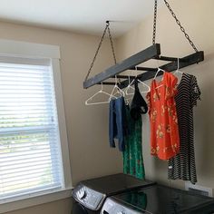 clothes are hanging from a drying rack in a laundry room