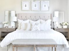 a bed with white sheets and pillows in a bedroom next to two framed pictures on the wall