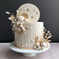 a white and gold decorated cake with flowers on the top, sitting on a plate