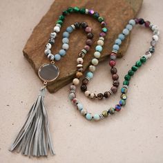 "Approx. 33\" L. Stone pendant approx. size: 1.1\"x5\" Color, pattern may vary. Elevate your boho-chic style with our captivating boho necklace adorned with a playful tassel pendant. This long beaded necklace features a harmonious blend of multi-color natural stones, including sea sediment jasper, aquamarine, and green malachite. Handmade and one-of-a-kind, this gemstone necklace is not only a fashion statement but also a source of crystal healing. With its approximate length of 33 inches, this knotted necklace drapes elegantly around your neck, adding a touch of natural beauty to any outfit. The stone tassel pendant, measuring approximately 1.1 inches by 5 inches, showcases the mesmerizing patterns and color variations characteristic of sea sediment jasper--a semi-precious stone known for Luxury Jasper Bohemian Necklace, Bohemian Hand-strung Amazonite Necklaces, Bohemian Long Hand-strung Turquoise Necklace, Bohemian Turquoise Multi-stone Necklace, Multi Gemstone Necklace, Blue Multi-stone Bohemian Turquoise Necklace, Green Malachite, Long Beaded Necklace, Knot Necklace