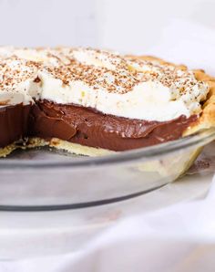 there is a pie with chocolate and whipped cream on top in the glass dish, ready to be eaten