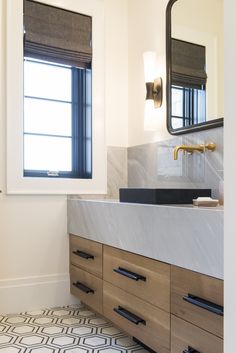 a bathroom with marble counter tops and wooden cabinets, along with a black and white patterned floor