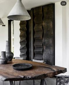 a wooden table with two vases on top of it next to a lamp hanging from the ceiling