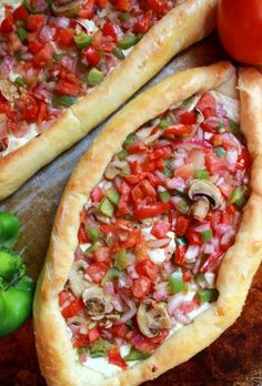 two pizzas with different toppings sitting on top of a cutting board next to a green pepper