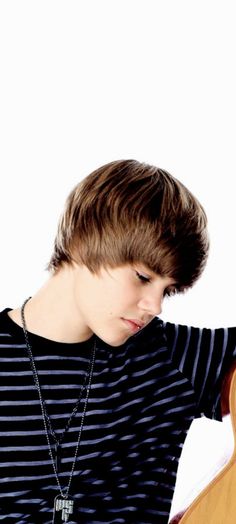 a young man holding a guitar in his hands and wearing a black striped t - shirt