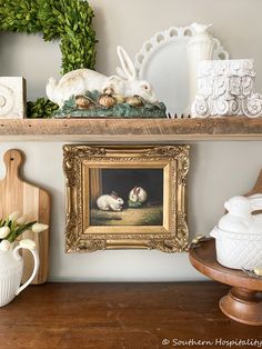 a shelf with some pictures and other items on it, including a framed bunny painting