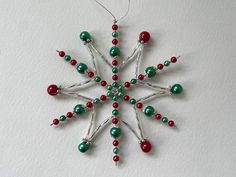 a snowflake ornament with red and green beads