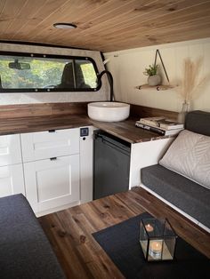 the interior of a camper with wood flooring and white walls, including a kitchen area