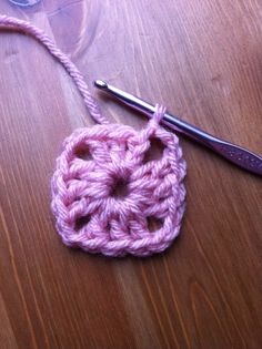 a crochet square is being worked on by a pair of scissors