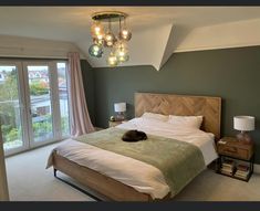 a bedroom with a large bed and two lamps hanging from the ceiling, next to a sliding glass door