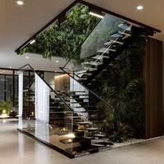 an indoor stair case with plants on the wall and glass railings to the second floor