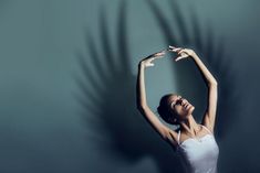 a woman in a white leotard stretching her arms