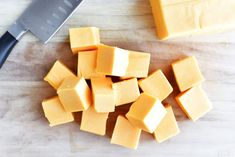 several cubes of cheese next to a knife on a cutting board