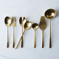 five gold spoons and six forks on a white surface