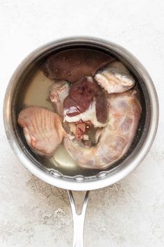 a pan filled with meat and vegetables on top of a counter next to a spoon