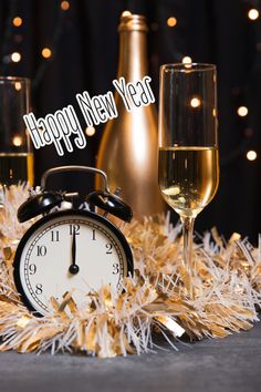 an alarm clock next to two glasses of champagne and a bottle of wine with the words happy new year written on it