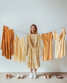 a woman standing in front of some clothes hanging on a line with shoes underneath her