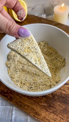 a person dipping something into a bowl with some sort of food in it on a wooden table