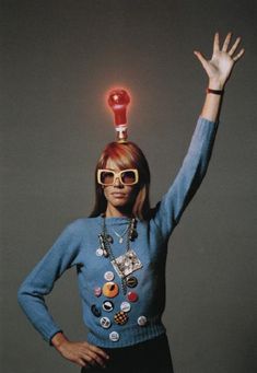 a woman with her hands up in the air while wearing glasses and a light bulb on top of her head