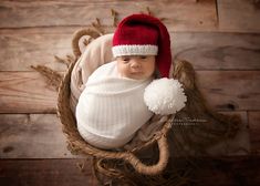 a baby wearing a red and white hat in a basket