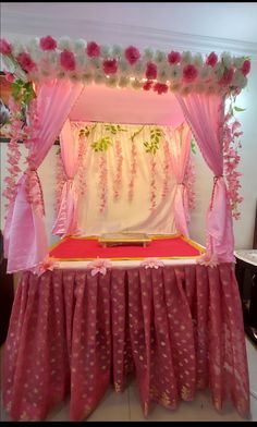 a bed covered in pink and white fabric with flowers on it's headboard