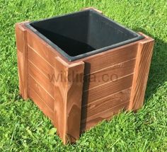 a wooden box sitting in the grass on top of some green grass with a black plastic container