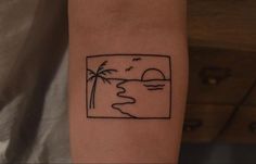 a small tattoo on the arm of a person with a sunset and palm trees in the background