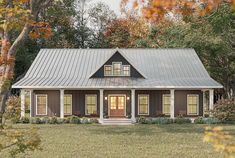 a house with a metal roof in the middle of some grass and trees around it