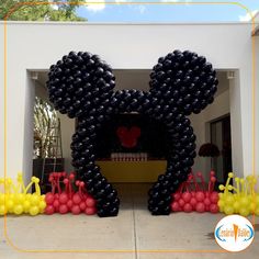 a mickey mouse balloon sculpture in front of a house with balloons surrounding it and an entrance