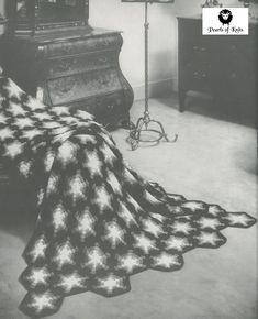 a black and white photo of a bed with a blanket on top of it next to a piano